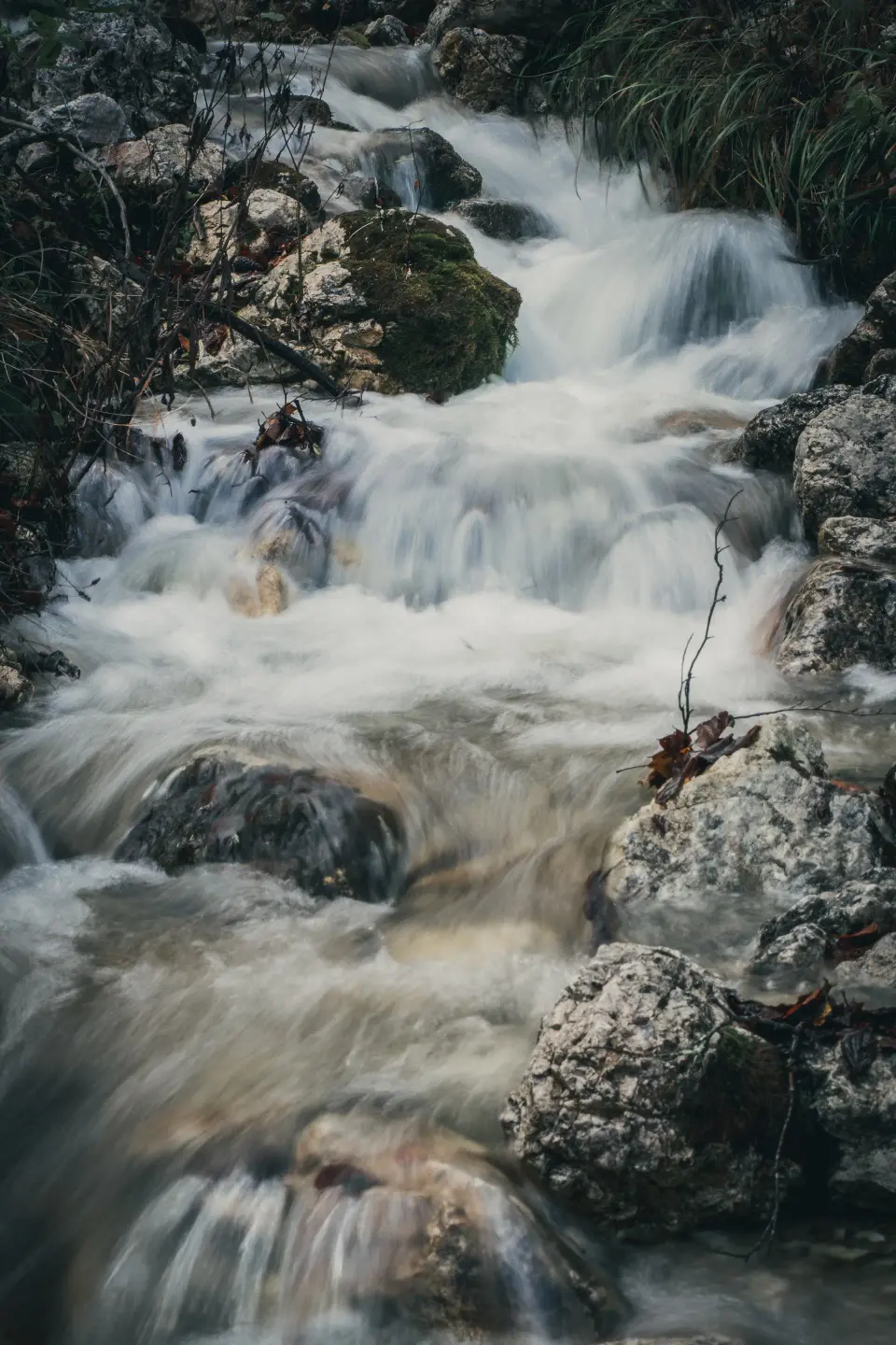 Cascata stretta tra rocce e muschio.