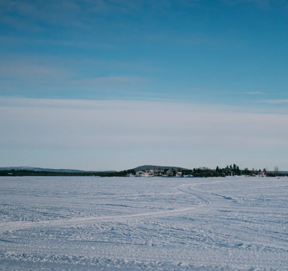 Paesaggio innevato con lago ghiacciato e cielo limpido.