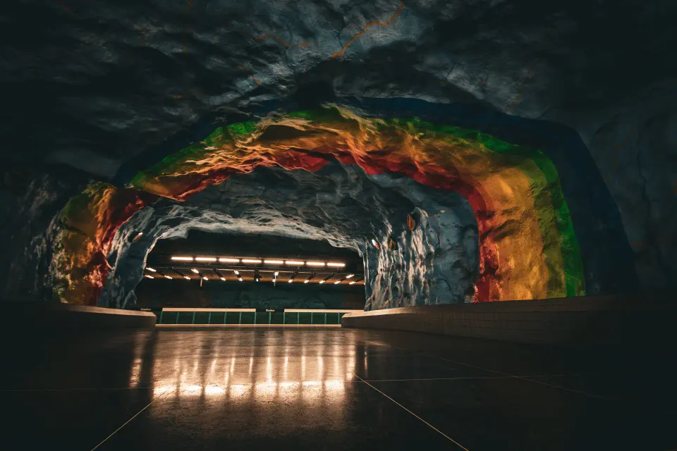 Galleria rocciosa illuminata con strada riflessa.