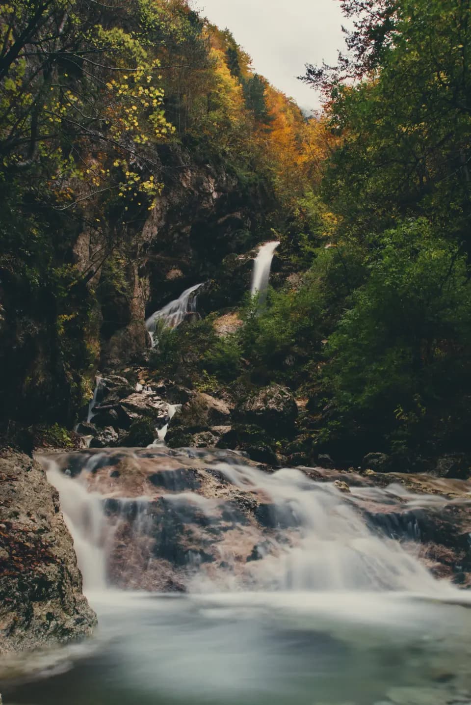 Cascata tra alberi autunnali.