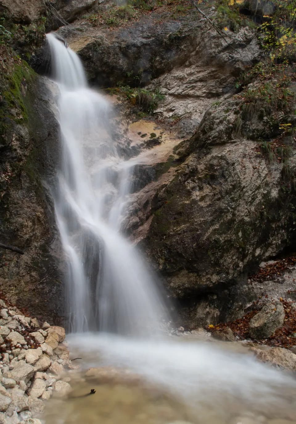 Cascata alta tra rocce chiare.