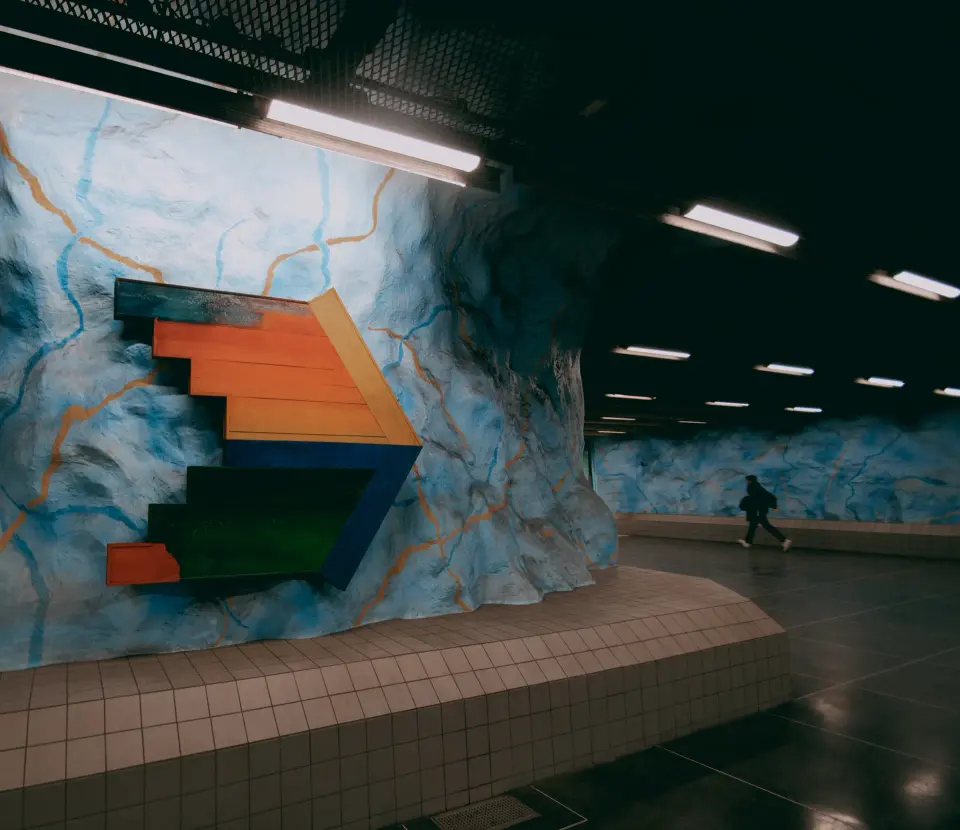 Banchina della metro con treno colorato in arrivo.