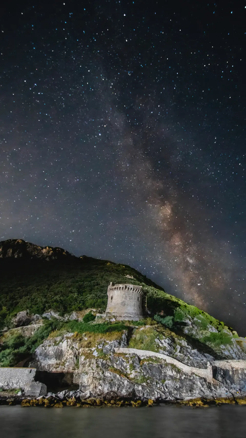 Paesaggio notturno con cielo stellato e una torre in primo piano