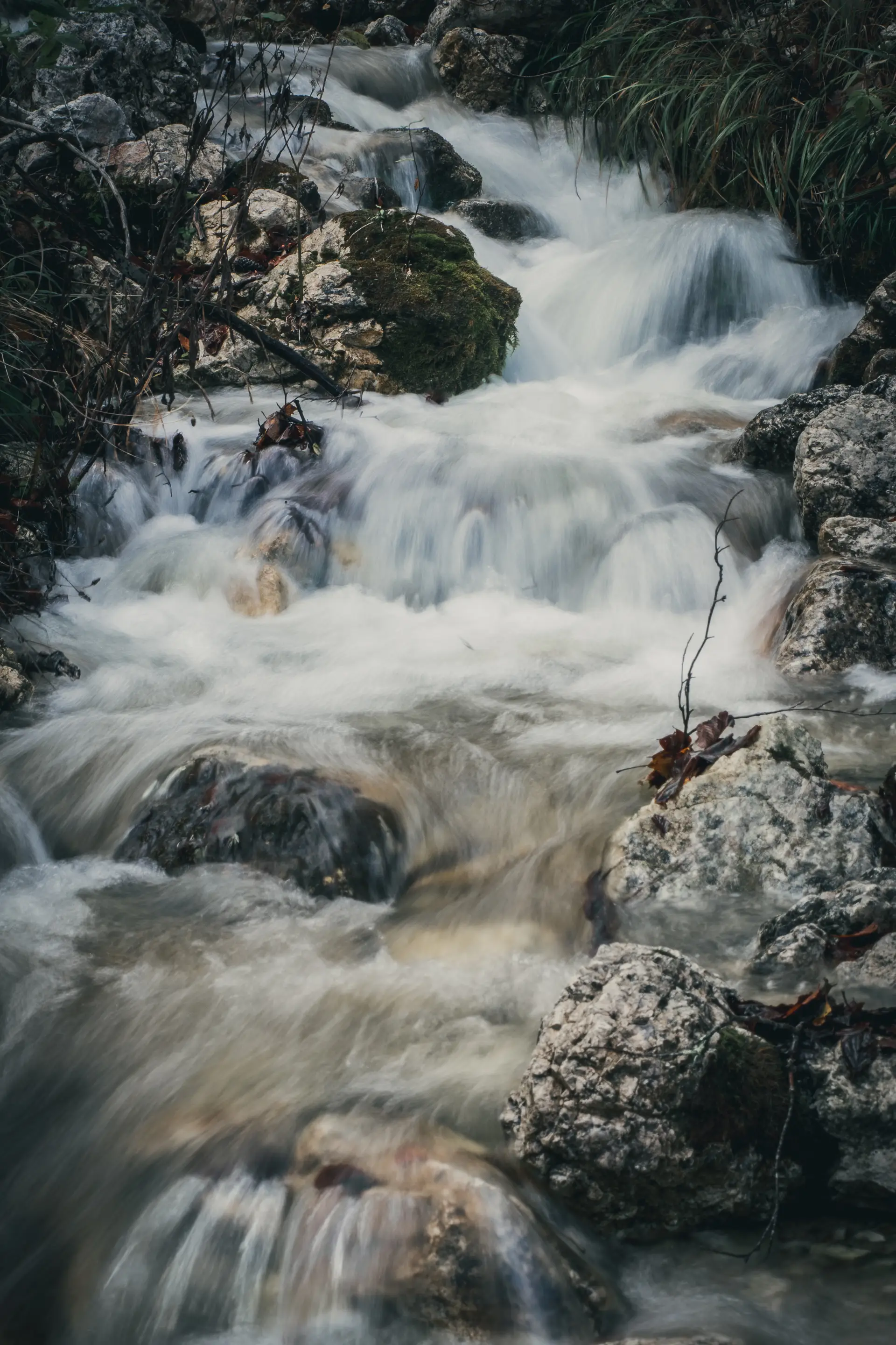 Cascata stretta tra rocce e muschio.